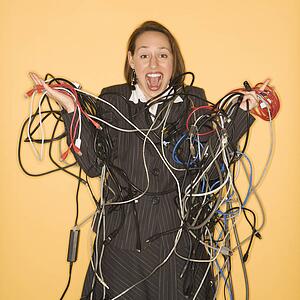 Smiling businesswoman holding tangled cables