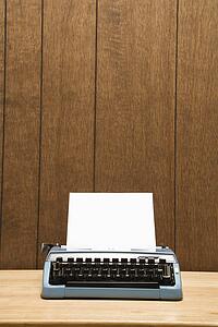 Vintage blue typewriter on desk with wood paneling.