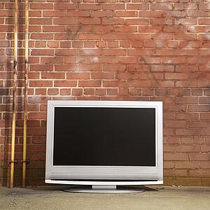 Flat panel television set in front of red brick wall