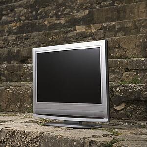 Flat panel television set in front of gray brick wall.