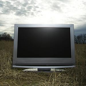 Flat panel television set in grassy field