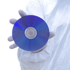 Close-up of man in biohazard suit and latex gloves holding compact disc