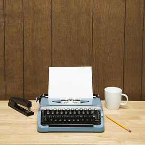 Vintage typewriter, coffee cup, pencil and stapler on desk.