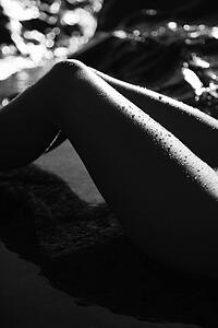 Filipino young woman's legs in water on rocky beach.