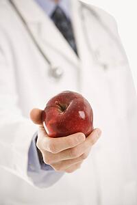 Mid adult male physician holding apple