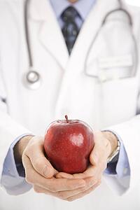 Mid adult male physician holding apple