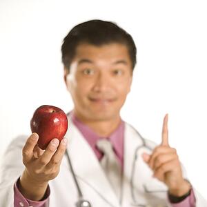 Male doctor holding out apple
