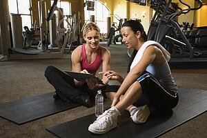 Adult female with personal trainer at gym