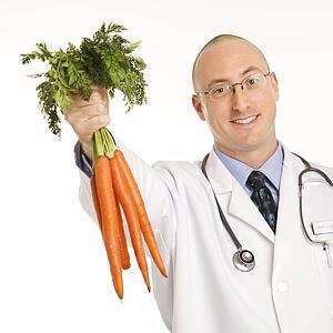 Male physician holding bunch of carrots