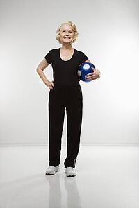 Senior woman standing holding soccer ball