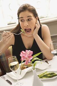 Woman making exaggerated expression while eating with fork to mouth