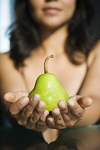 Woman holding pear in outstretched hands toward viewer.