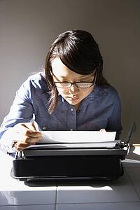 Woman sitting in chair typing on typewriter in kitchen