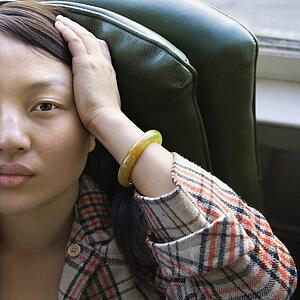 Woman sitting in green chair with hands on her head