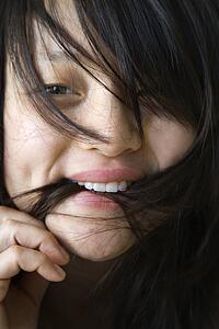 Close up portrait of pretty young Asian woman biting her hair.