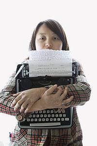 Pretty young Asian woman holding typewriter.