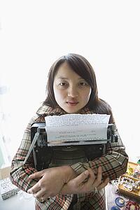 Pretty young woman holding typewriter