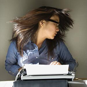 Pretty young woman sitting at typewriter swinging head and hair around