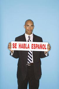 Man holding sign reading se habla espanol against blue background