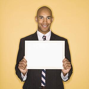 Man smiling holding blank sign against yellow background