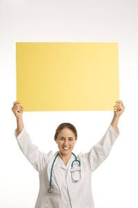 Portrait of doctor holding up blank yellow sign smiling and looking at viewer
