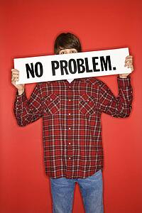 Portrait of boy holding no problem sign under his eyes