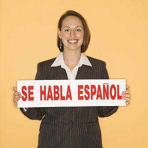 Businesswoman smiling holding sign reading 'se habla espanol. '