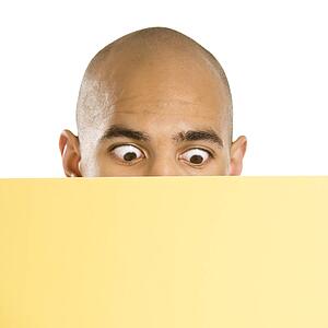 Man peeking over blank yellow sign