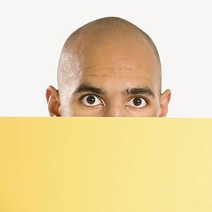 Man peeking over blank yellow sign