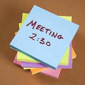 Stack of sticky notes with a meeting reminder