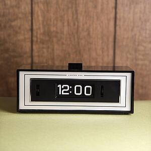 Retro clock set for 12: 00 against wood paneling.