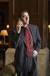 Caucasian mid adult buisinessman on cell phone with hand on hip.