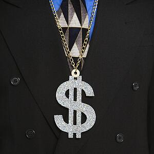 Man in suit wearing necklace with money sign.