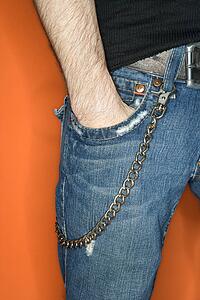 Young adult Caucasian male with hands in jean pocket and wallet chain.