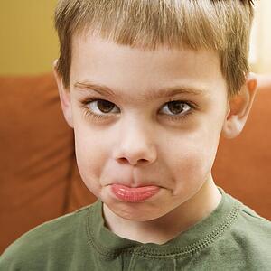 Young boy pouting and looking at viewer.