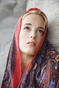 Portrait of Caucasian young adult woman with scarf draped over head looking up.