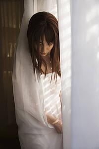 woman standing in sunlit curtains.