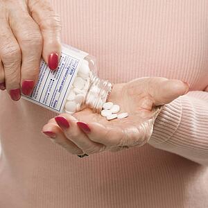 Female hands pouring pills from container