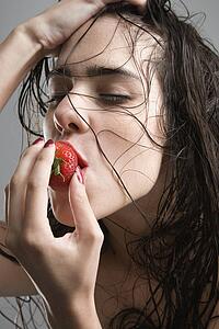 Topless caucasian woman biting a strawberry.