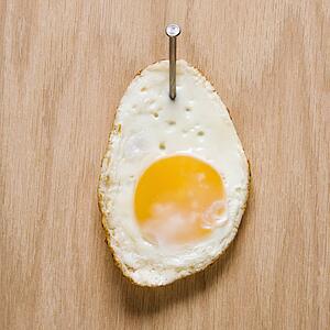 Fried egg nailed to wood.