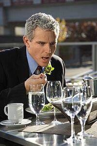 Man sitting at outside patio table eating salad