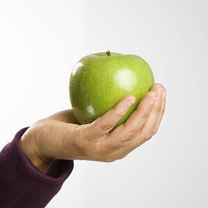 Woman holding out green apple in hand