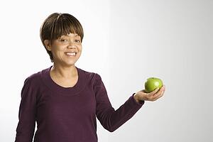 Portrait of woman holding green apple smiling and looking at viewer