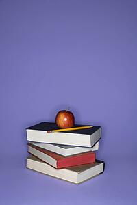 Stack of books with apple and pencil.