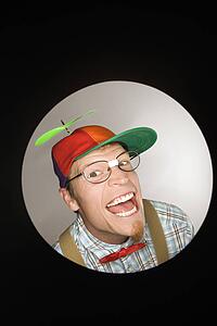 Close up circle vignette of Caucasian young man dressed like nerd wearing propeller cap with mischievous look.