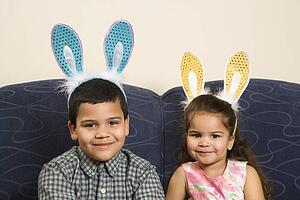 Brother and sister wearing bunny ears smiling and looking at viewer