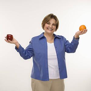 woman holding fruit in outstretched arms and smiling 