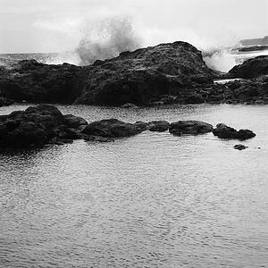 Landscape of waves crashing into rocky Hawaii coast.