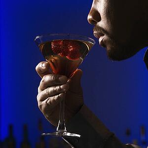 man drinking martini in bar against glowing blue background
