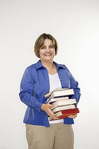 Mature woman holding stack of books.